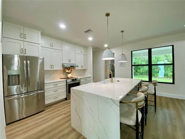 3616 Bellefonte Ave, North Port, FL 34286 - kitchen featuring stainless steel appliances, under cabinet range hood, light wood-style floors, tasteful backsplash, and white cabinetry