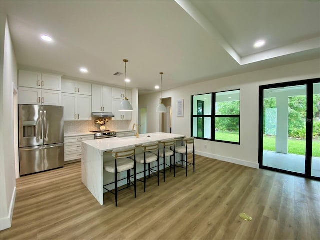 3616 Bellefonte Ave, North Port, FL 34286 - kitchen featuring appliances with stainless steel finishes, light wood-style floors, tasteful backsplash, light countertops, and a center island with sink