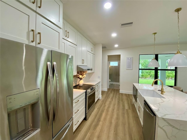 3616 Bellefonte Ave, North Port, FL 34286 - kitchen with appliances with stainless steel finishes, light wood-style floors, white cabinets, under cabinet range hood, and pendant lighting