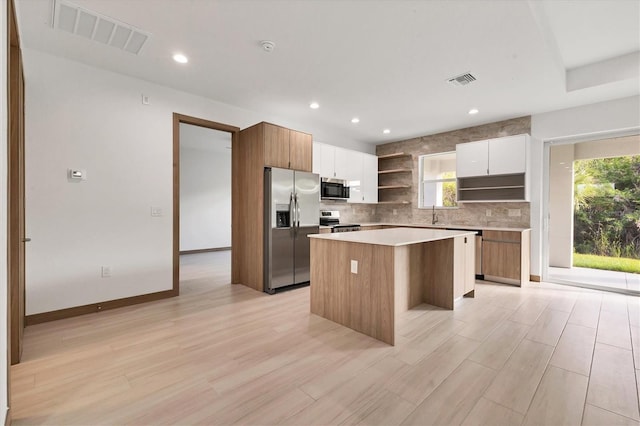 405 Sunset Rd N, Rotonda West, FL 33947 - kitchen with appliances with stainless steel finishes, open shelves, a center island, decorative backsplash, and modern cabinets