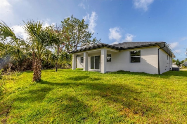405 Sunset Rd N, Rotonda West, FL 33947 - rear view of house featuring stucco siding and a lawn