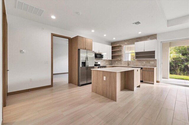 299 Australian Dr, Rotonda West, FL 33947 - kitchen with appliances with stainless steel finishes, open shelves, a center island, backsplash, and modern cabinets