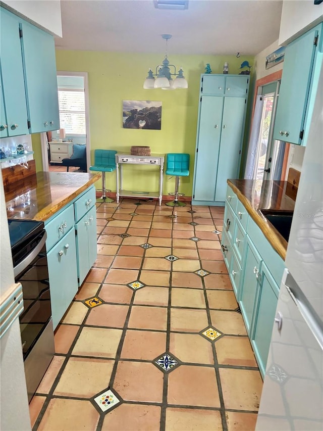 3767 Pinstar Ter, North Port, FL 34287 - kitchen featuring stainless steel range with electric stovetop, blue cabinets, a chandelier, hanging light fixtures, and light tile patterned floors