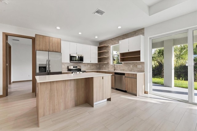 102 Arrow Ln, Rotonda West, FL 33947 - kitchen with stainless steel appliances, open shelves, a center island, backsplash, and light countertops