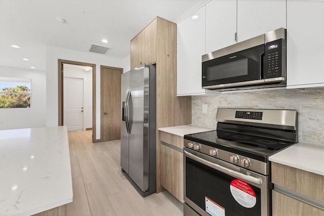 102 Arrow Ln, Rotonda West, FL 33947 - kitchen with appliances with stainless steel finishes, tasteful backsplash, light stone counters, light wood-type flooring, and recessed lighting
