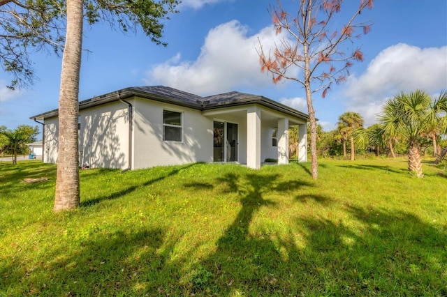102 Arrow Ln, Rotonda West, FL 33947 - rear view of house with stucco siding and a lawn