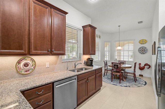 5662 Fossano Dr, Sarasota, FL 34238 - kitchen featuring appliances with stainless steel finishes, backsplash, light stone countertops, hanging light fixtures, and light tile patterned flooring