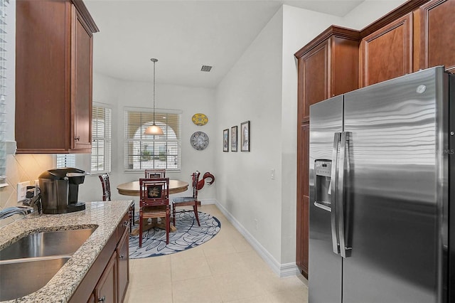 5662 Fossano Dr, Sarasota, FL 34238 - kitchen with stainless steel fridge, light stone countertops, pendant lighting, tasteful backsplash, and light tile patterned floors