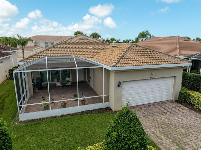 5662 Fossano Dr, Sarasota, FL 34238 - back of house with an attached garage, stucco siding, decorative driveway, a tiled roof, and a yard