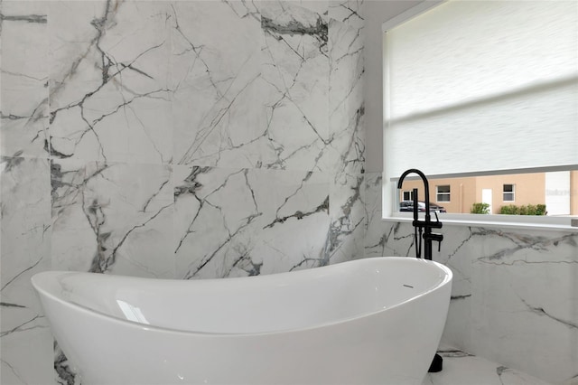 920 Lena Ln, Sarasota, FL 34240 - full bath featuring marble tiled floors, a soaking tub, stone wall, and tile walls