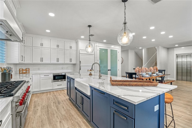 119 Avenida Messina, Sarasota, FL 34242 - kitchen featuring extractor fan, blue cabinetry, white cabinetry, appliances with stainless steel finishes, and recessed lighting