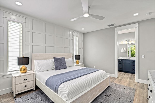 119 Avenida Messina, Sarasota, FL 34242 - bedroom with light wood finished floors, recessed lighting, connected bathroom, a ceiling fan, and a decorative wall