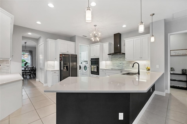 16038 39th Gln E, Parrish, FL 34219 - kitchen with wall chimney exhaust hood, black appliances, washer and clothes dryer, tasteful backsplash, and light tile patterned floors