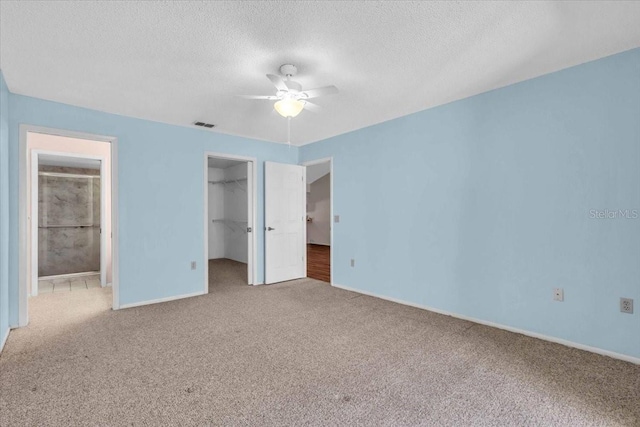 327 40th Ct W, Palmetto, FL 34221 - unfurnished bedroom with carpet flooring, a spacious closet, a closet, a textured ceiling, and a ceiling fan