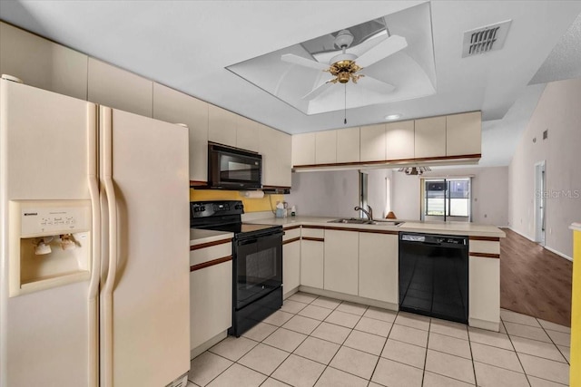 327 40th Ct W, Palmetto, FL 34221 - kitchen featuring black appliances, cream cabinets, a tray ceiling, light countertops, and a peninsula