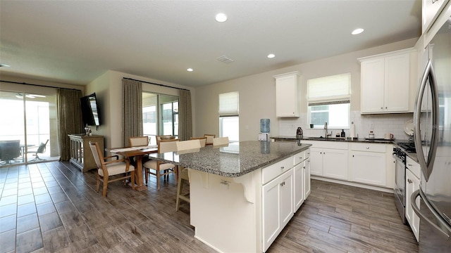 11223 Spring Gate Trl, Bradenton, FL 34211 - kitchen featuring a kitchen island, white cabinets, tasteful backsplash, a kitchen breakfast bar, and dark stone counters