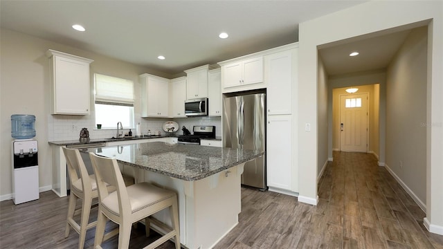 11223 Spring Gate Trl, Bradenton, FL 34211 - kitchen with stainless steel appliances, a kitchen island, backsplash, dark wood-type flooring, and white cabinets