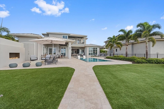 676 Regatta Way, Bradenton, FL 34208 - back of house with a patio area, a lit fireplace, stucco siding, and a standing seam roof