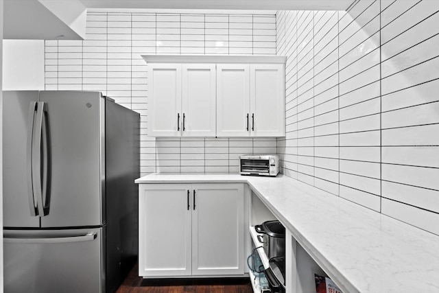 676 Regatta Way, Bradenton, FL 34208 - kitchen with freestanding refrigerator, decorative backsplash, white cabinetry, and light stone counters