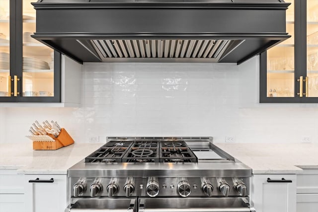 676 Regatta Way, Bradenton, FL 34208 - kitchen view of stainless steel gas stove, premium range hood, backsplash, and glass insert cabinets