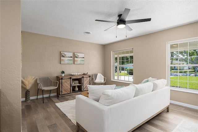 616 59th St NW, Bradenton, FL 34209 - living room featuring healthy amount of natural light, a textured ceiling, wood-type flooring, a ceiling fan, and a textured wall