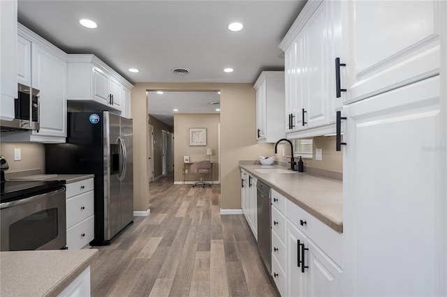 616 59th St NW, Bradenton, FL 34209 - kitchen featuring appliances with stainless steel finishes, white cabinetry, light wood-style floors, light countertops, and recessed lighting