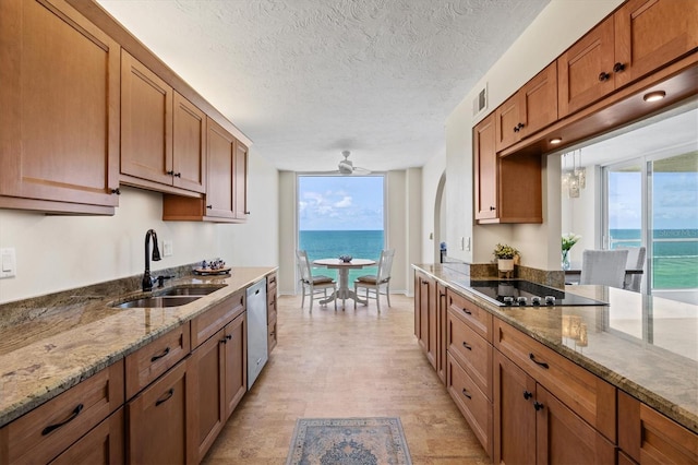2425 Gulf Of Mexico Dr Unit 10F, Longboat Key, FL 34228 - kitchen featuring black electric stovetop, brown cabinets, stone counters, ceiling fan, and a textured ceiling
