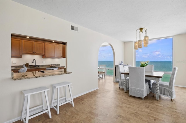 2425 Gulf Of Mexico Dr Unit 10F, Longboat Key, FL 34228 - dining area with light wood finished floors, a chandelier, a textured ceiling, and a water view