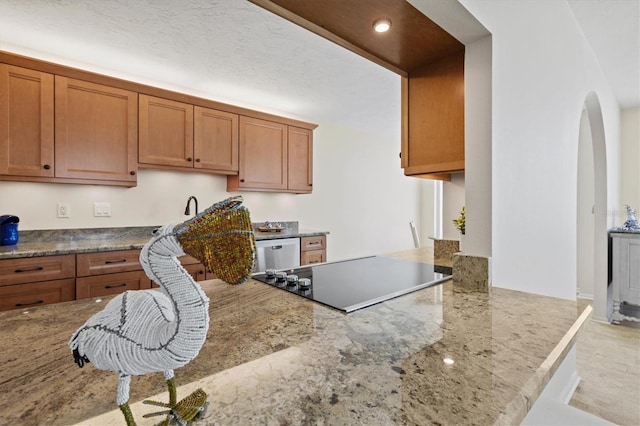 2425 Gulf Of Mexico Dr Unit 10F, Longboat Key, FL 34228 - kitchen with arched walkways, black electric cooktop, brown cabinetry, light stone counters, and recessed lighting