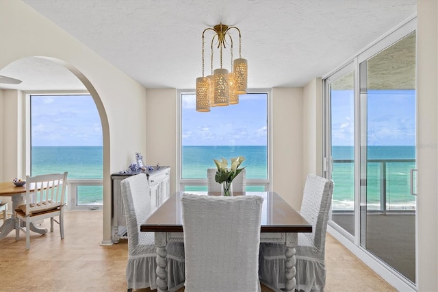 2425 Gulf Of Mexico Dr Unit 10F, Longboat Key, FL 34228 - dining space with arched walkways, a water view, a chandelier, and a textured ceiling