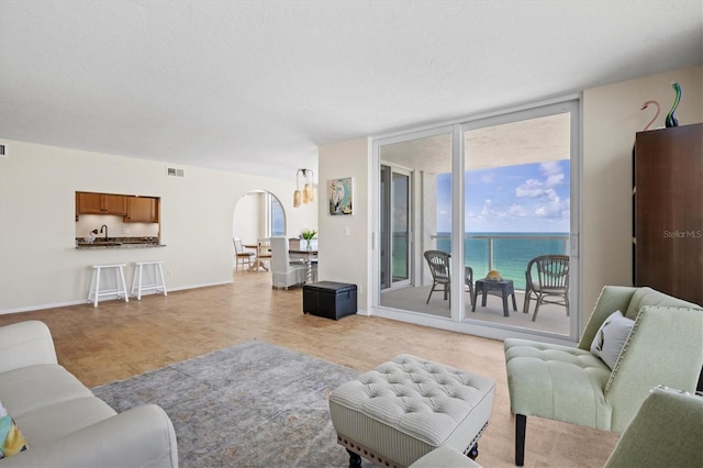 2425 Gulf Of Mexico Dr Unit 10F, Longboat Key, FL 34228 - living area with arched walkways, a water view, floor to ceiling windows, and a textured ceiling