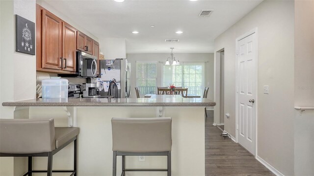 8907 White Sage Loop, Lakewood Ranch, FL 34202 - kitchen featuring appliances with stainless steel finishes, brown cabinets, a peninsula, a kitchen breakfast bar, and recessed lighting