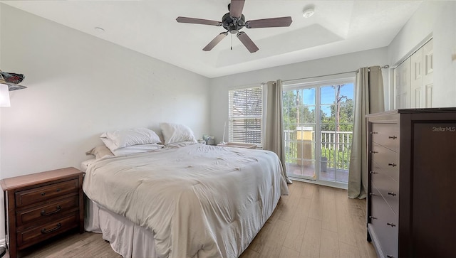 8907 White Sage Loop, Lakewood Ranch, FL 34202 - bedroom featuring access to exterior, light wood-style flooring, a tray ceiling, and a ceiling fan