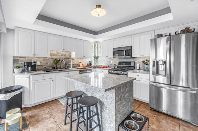 200 Cocoanut Ave Unit 1, Sarasota, FL 34236 - kitchen featuring appliances with stainless steel finishes, a tray ceiling, light tile patterned floors, decorative backsplash, and white cabinets