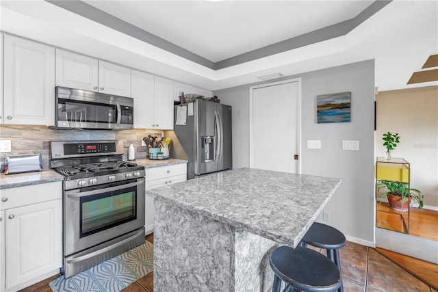 200 Cocoanut Ave Unit 1, Sarasota, FL 34236 - kitchen with appliances with stainless steel finishes, dark tile patterned floors, white cabinetry, and backsplash