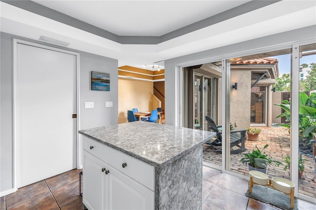 200 Cocoanut Ave Unit 1, Sarasota, FL 34236 - kitchen featuring white cabinetry, a kitchen island, light tile patterned flooring, and light stone countertops