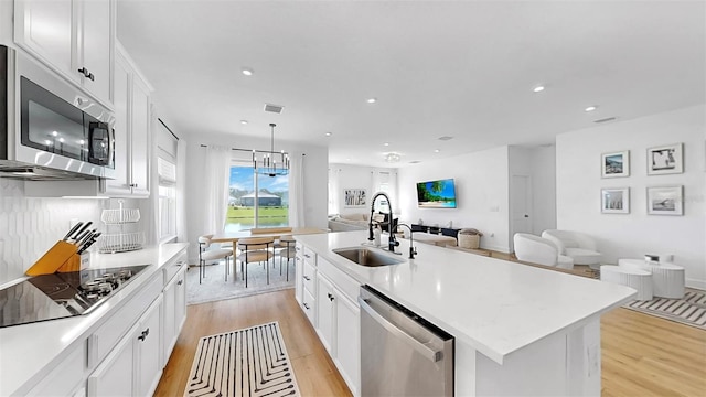 6120 115th Ave E, Parrish, FL 34219 - kitchen featuring stainless steel appliances, open floor plan, light wood finished floors, white cabinets, and light countertops