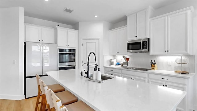 6120 115th Ave E, Parrish, FL 34219 - kitchen featuring stainless steel appliances, white cabinets, an island with sink, a kitchen bar, and recessed lighting