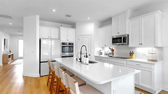 6120 115th Ave E, Parrish, FL 34219 - kitchen featuring stainless steel appliances, a center island with sink, light wood-style floors, white cabinetry, and recessed lighting