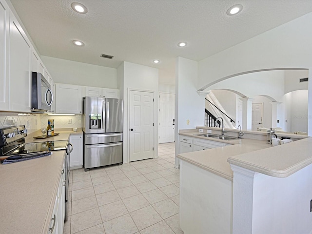 5184 51st Ln W, Bradenton, FL 34210 - kitchen with stainless steel appliances, arched walkways, decorative columns, white cabinetry, and light countertops