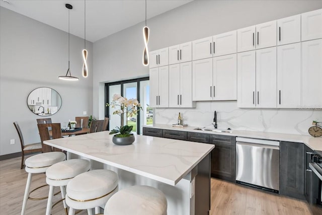 9150 Key W St, Port Charlotte, FL 33981 - kitchen featuring stainless steel dishwasher, a towering ceiling, light wood finished floors, light stone countertops, and pendant lighting