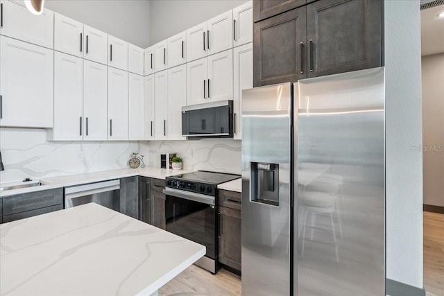 9150 Key W St, Port Charlotte, FL 33981 - kitchen with appliances with stainless steel finishes, light stone countertops, light wood-type flooring, and tasteful backsplash