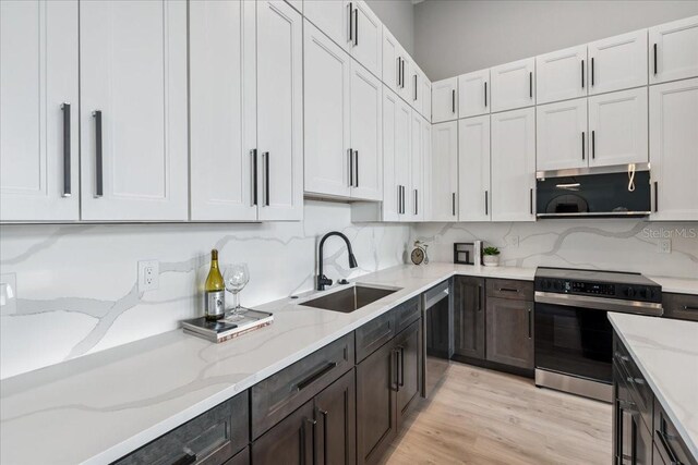 9150 Key W St, Port Charlotte, FL 33981 - kitchen with stainless steel appliances, white cabinetry, light stone countertops, light wood-style flooring, and dark brown cabinets