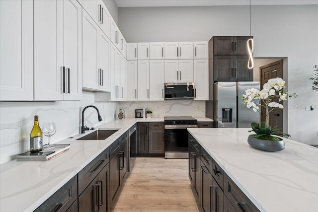 9150 Key W St, Port Charlotte, FL 33981 - kitchen featuring stainless steel appliances, decorative backsplash, light wood-style flooring, white cabinetry, and light stone counters