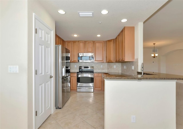 318 Winding Brook Ln Unit 104, Bradenton, FL 34212 - kitchen featuring stainless steel appliances, light tile patterned flooring, stone counters, a peninsula, and decorative backsplash