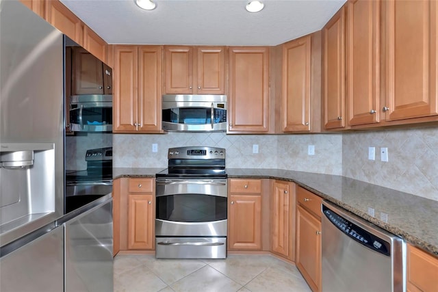 318 Winding Brook Ln Unit 104, Bradenton, FL 34212 - kitchen featuring stainless steel appliances, dark stone counters, light tile patterned floors, tasteful backsplash, and recessed lighting