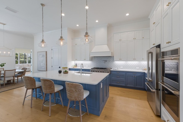 16511 Cornwall Ln, Lakewood Ranch, FL 34202 - kitchen with appliances with stainless steel finishes, blue cabinets, custom exhaust hood, backsplash, and white cabinets