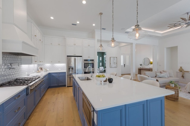 16511 Cornwall Ln, Lakewood Ranch, FL 34202 - kitchen featuring blue cabinets, custom exhaust hood, stainless steel appliances, open floor plan, and white cabinets