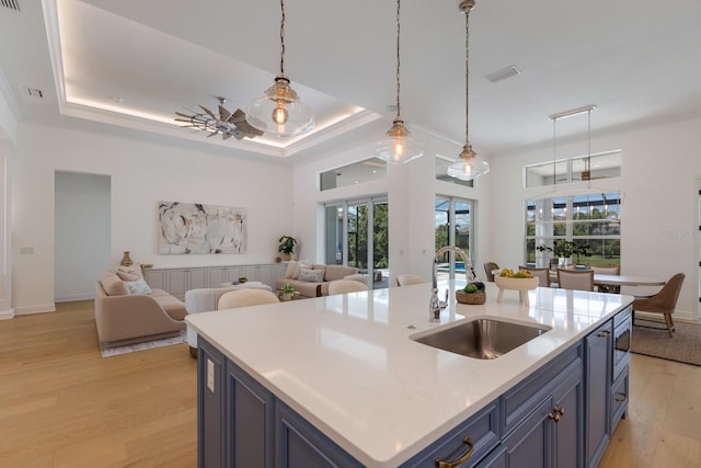 16511 Cornwall Ln, Lakewood Ranch, FL 34202 - kitchen featuring light wood finished floors, open floor plan, light countertops, pendant lighting, and blue cabinets