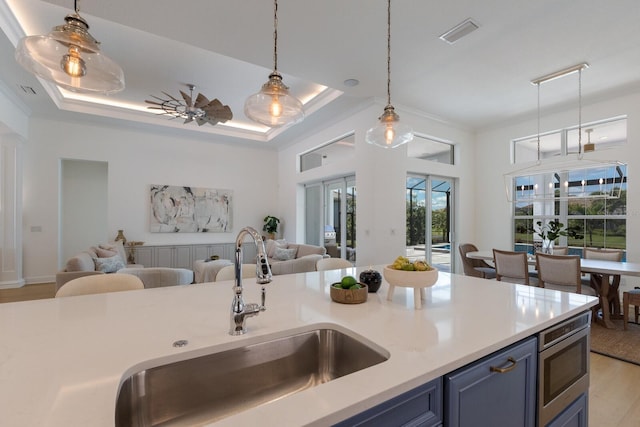 16511 Cornwall Ln, Lakewood Ranch, FL 34202 - kitchen with open floor plan, blue cabinetry, stainless steel microwave, and light countertops